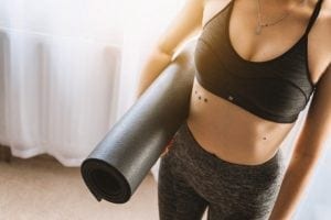 Woman holding a yoga mat post workout